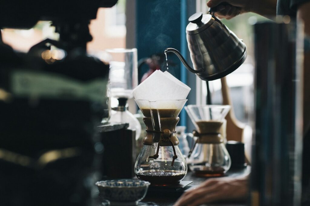 Hot water poured from a gooseneck kettle into a paper filter for pour-over coffee.